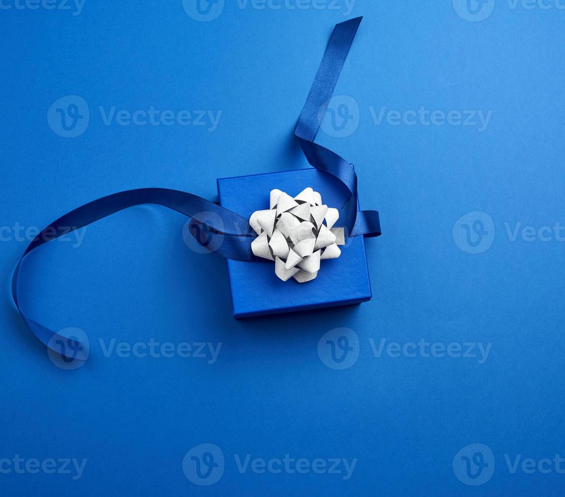 blue square box with a gift with a bow on a blue classic background, top view photo
