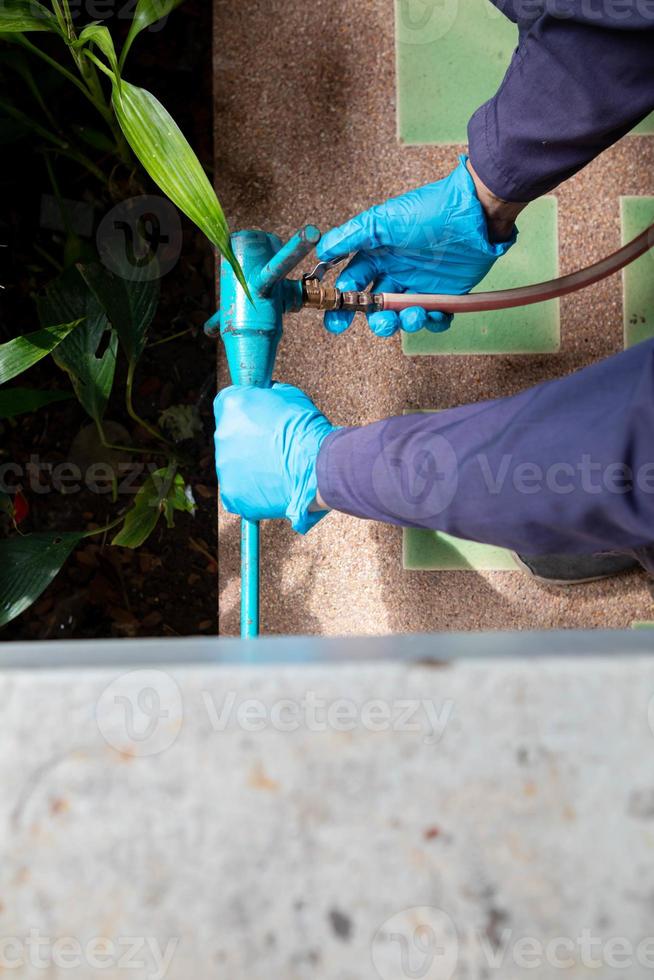 exterminate termite control company employee is using a termite sprayer at customer's house and searching for termite nests to eliminate. exterminate control worker spraying chemical insect repellant photo