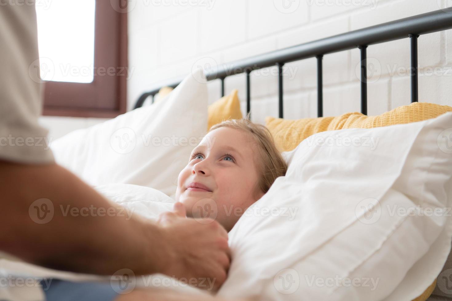 antes de saliente a noche, un padre expresa su afecto por besos su hija en el frente. a obtener un bueno de la noche descanso foto