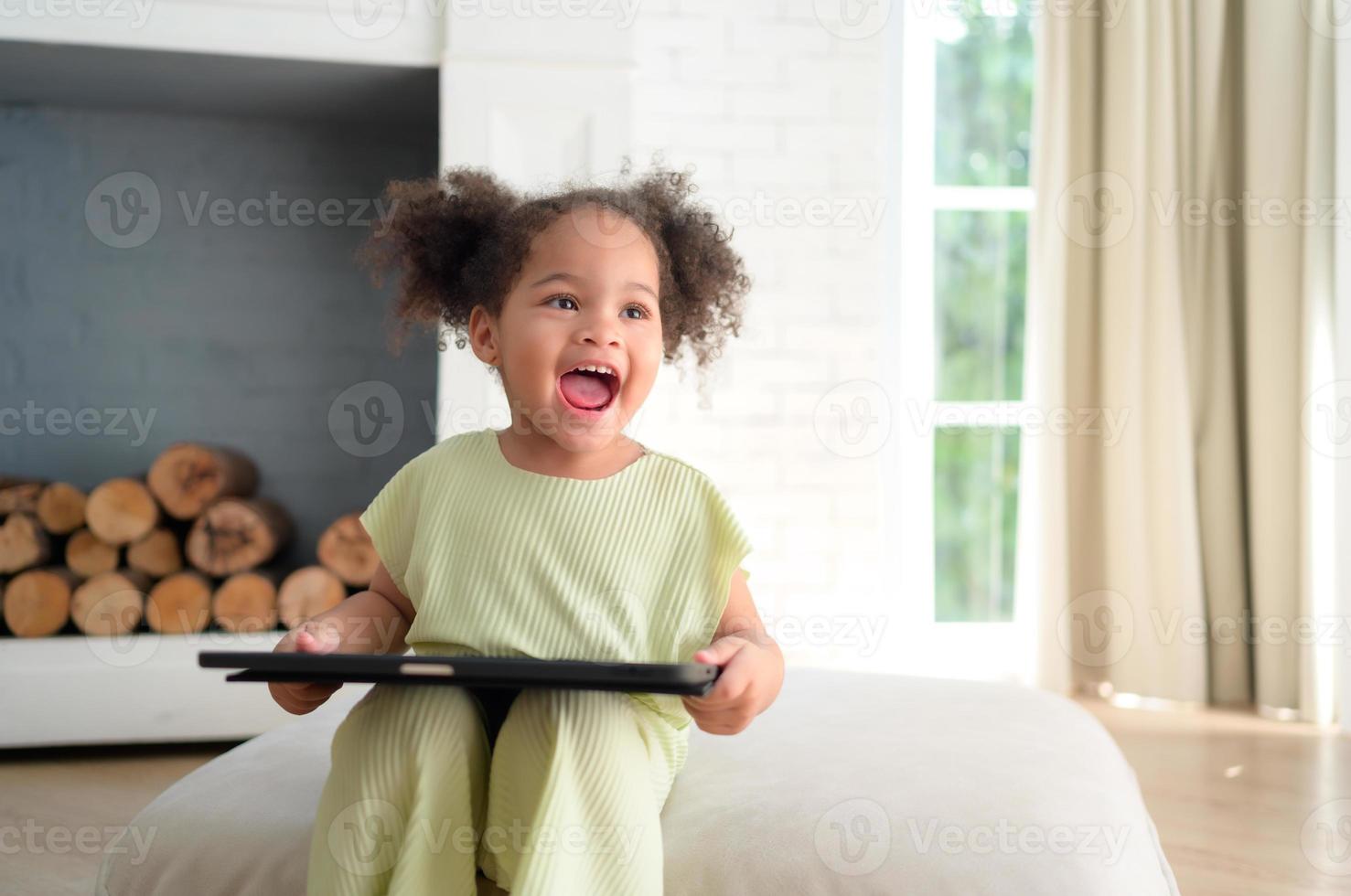 un joven brillante linda pequeño niña con su fiel tableta ese hace su contento y alegre. foto