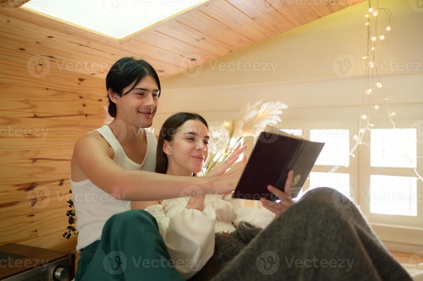 Young couple having fun and enjoyment reading folk novels to one another in the morning in the attic bedroom. photo