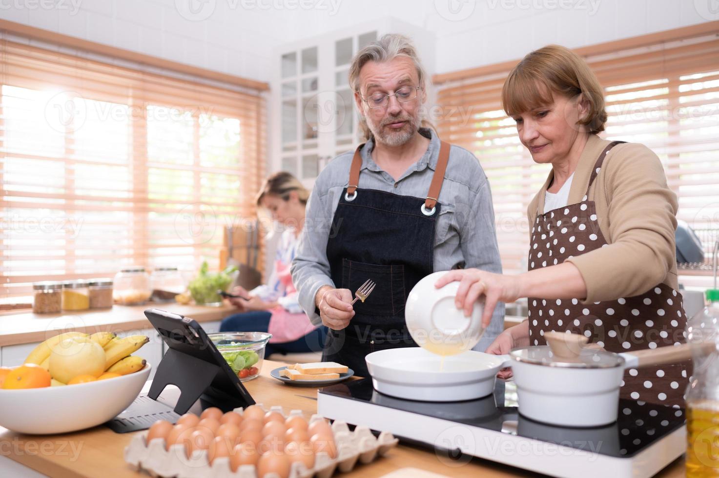 Grandparents with grandchildren and daughter gather in the kitchen to prepare the day's dinner. photo