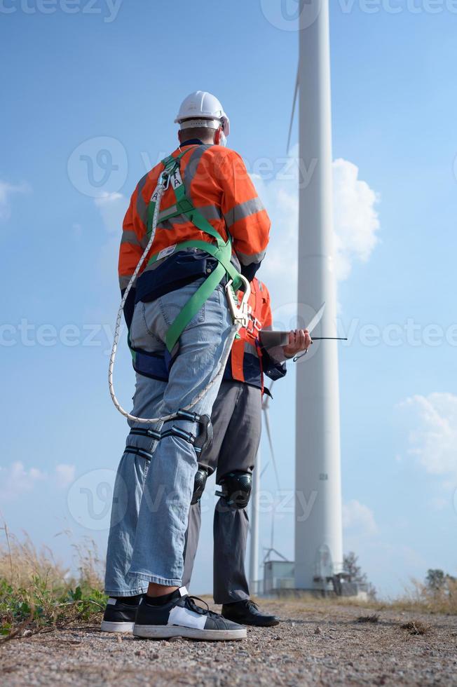 Surveyor and engineer Examine the efficiency of gigantic wind turbines that transform wind energy into electrical energy that is then used in daily life. photo