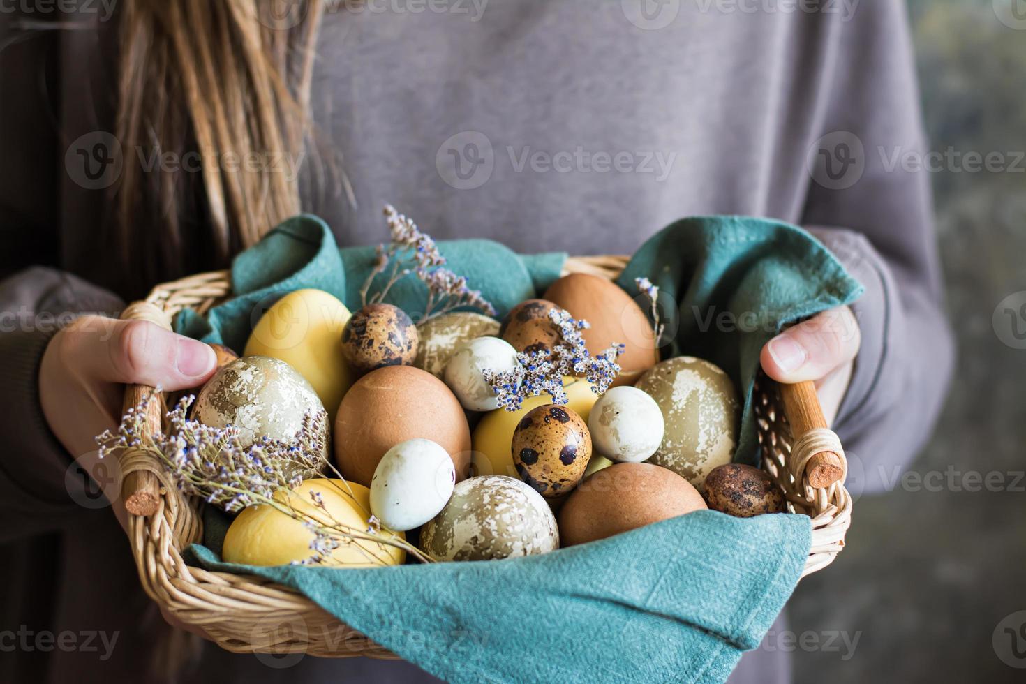 Basket in female hands with eggs dyed with turmeric, hibiscus and black tea in an eco-friendly way photo