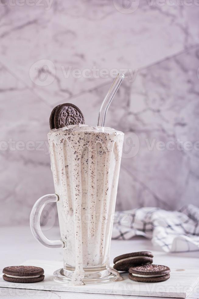 Milkshake of chocolate oreo cookies and ice cream in a glass with a straw vertical view photo