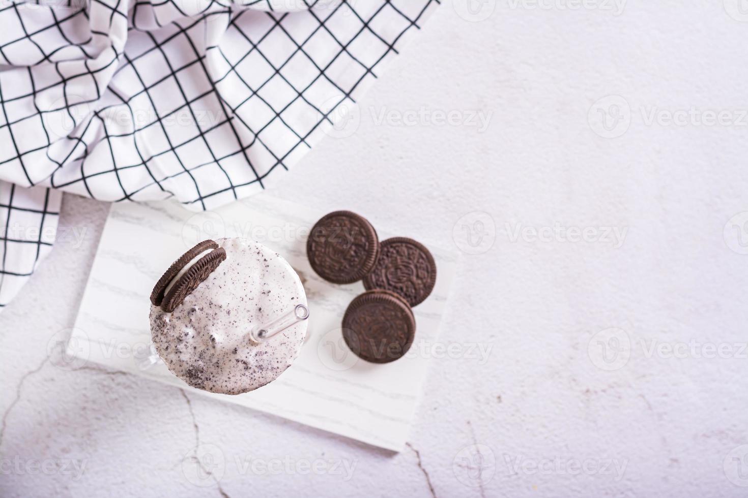 Milkshake of chocolate oreo cookies and ice cream in a glass with a straw top view photo