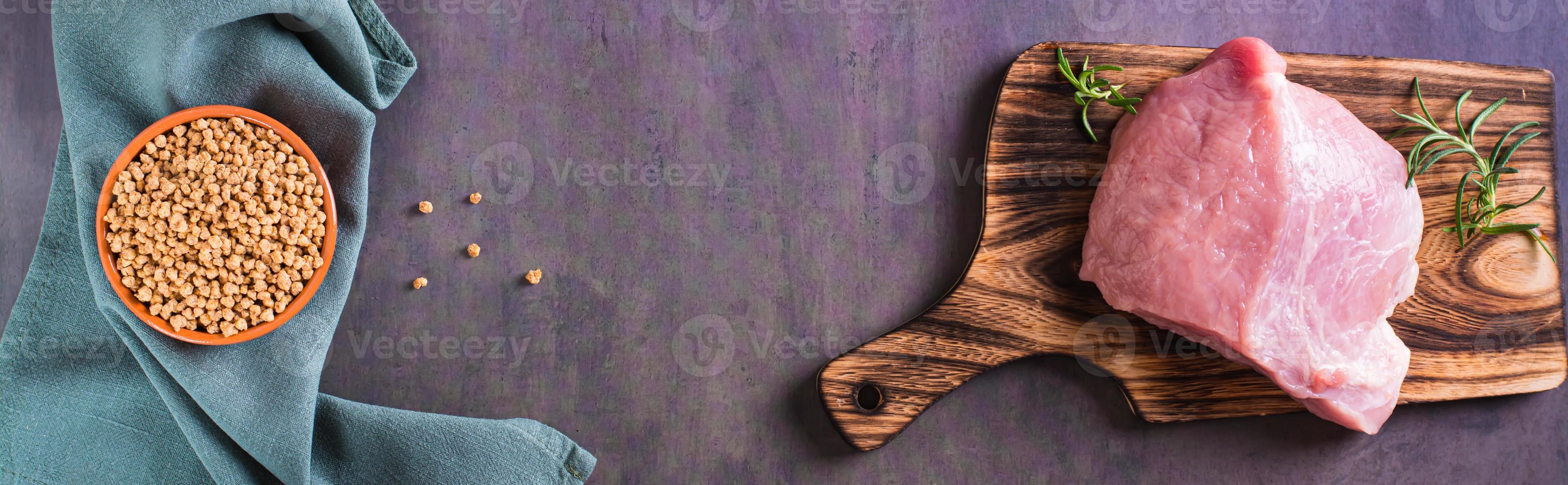 A piece of fresh meat on a cutting board and soy mince in a bowl top view web banner photo