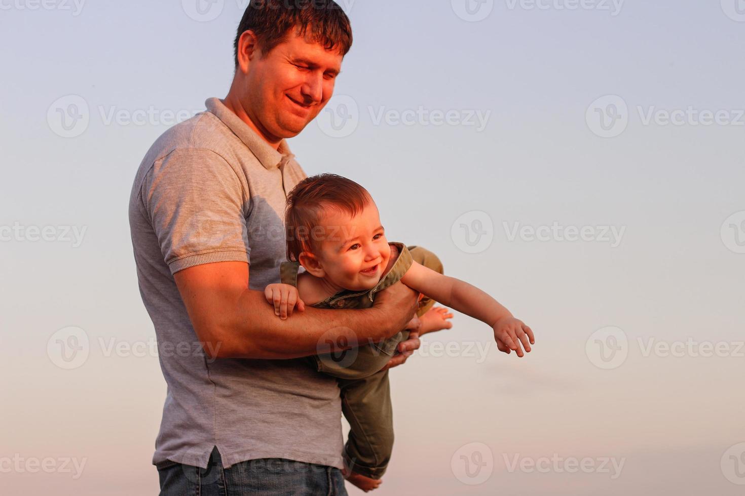 Happy dad and son have fun on the field on a hot summer day. Concept of friendly family and of summer vacation photo