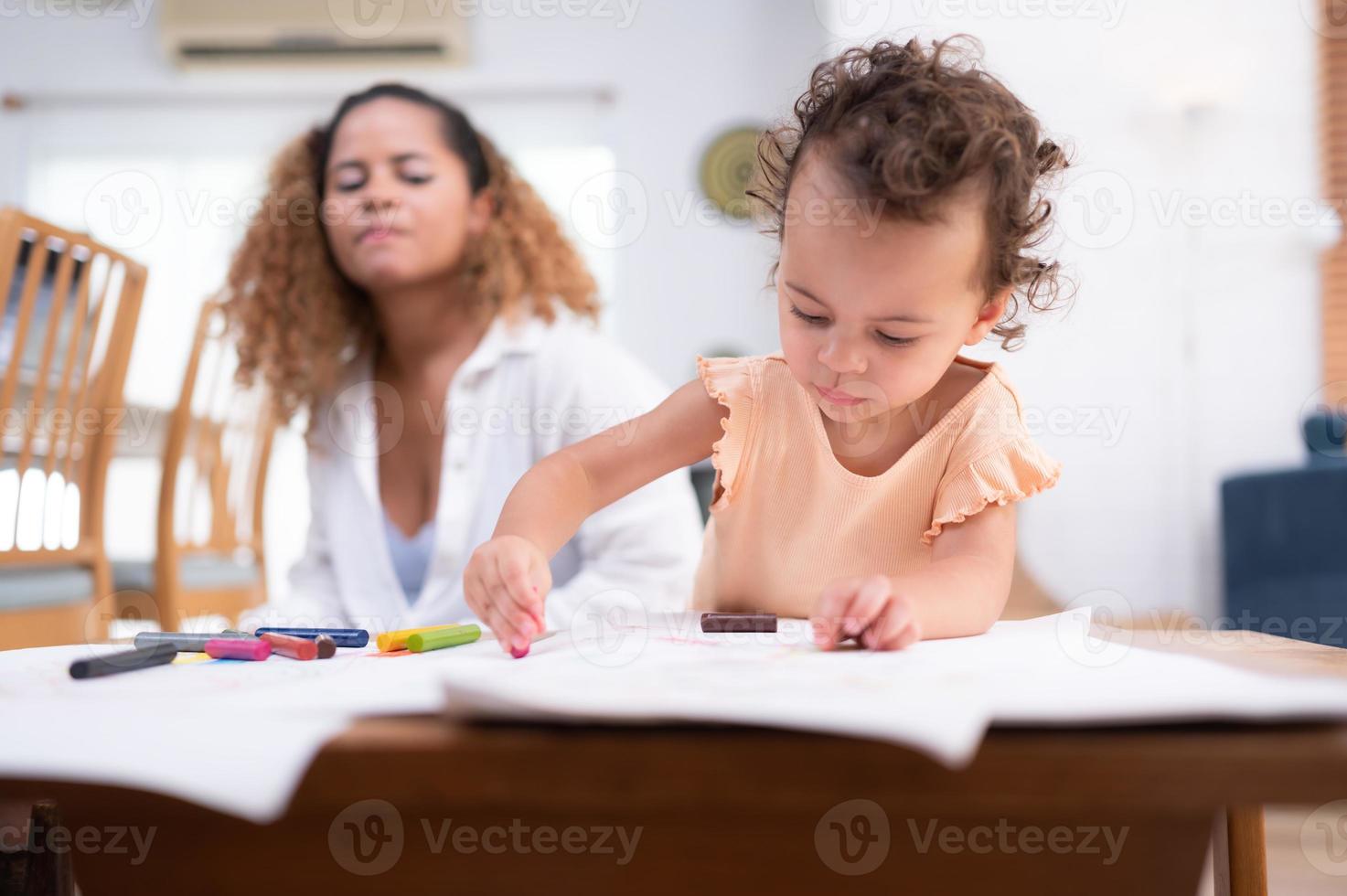 un pequeño niño imaginación es representado mediante de colores lápiz dibujos, con el madre atentamente supervisando en el vivo habitación de el casa. foto