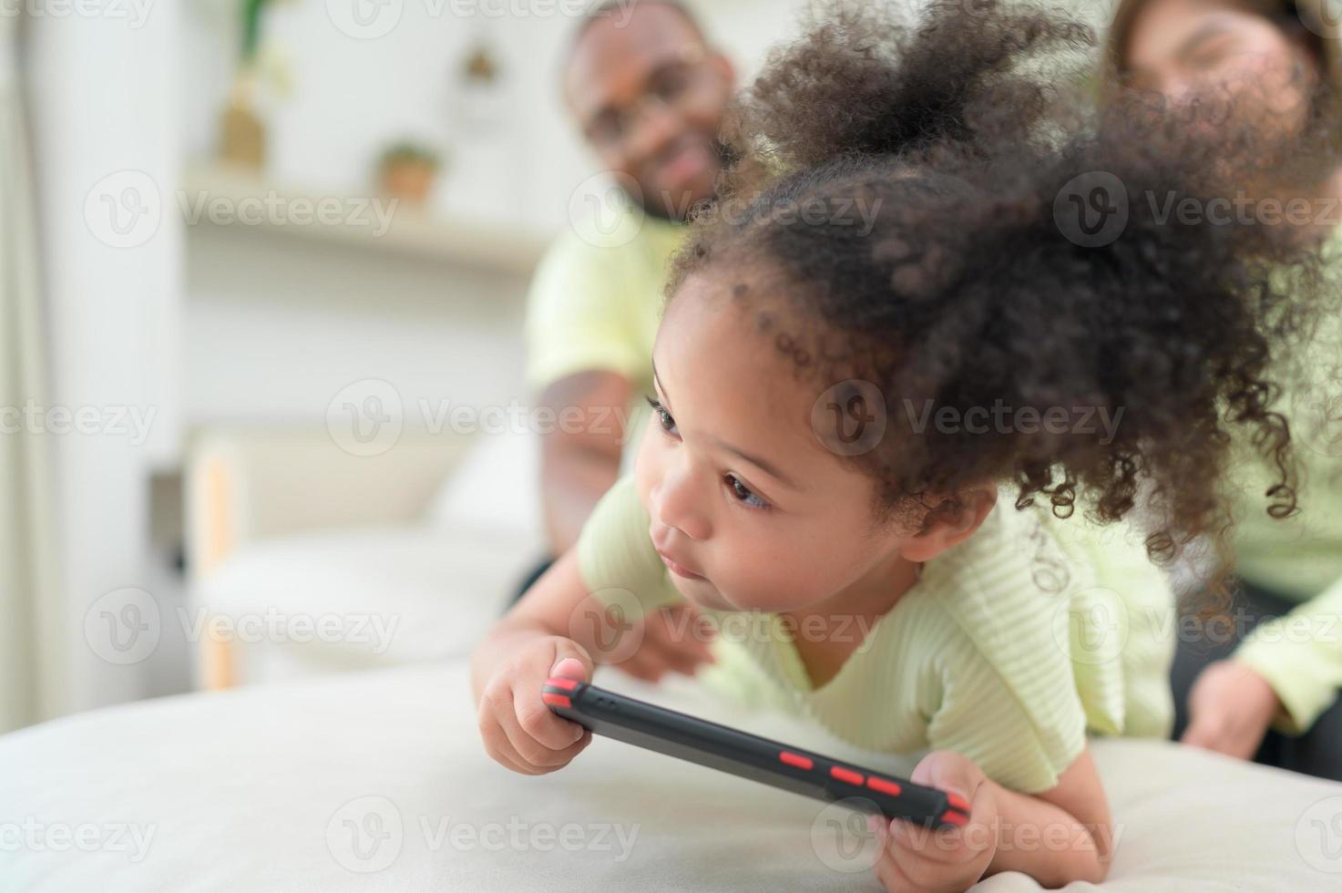 Little children play and learn things in the wide world on tablet. with parents to supervise and help in the living room of the house on vacation photo