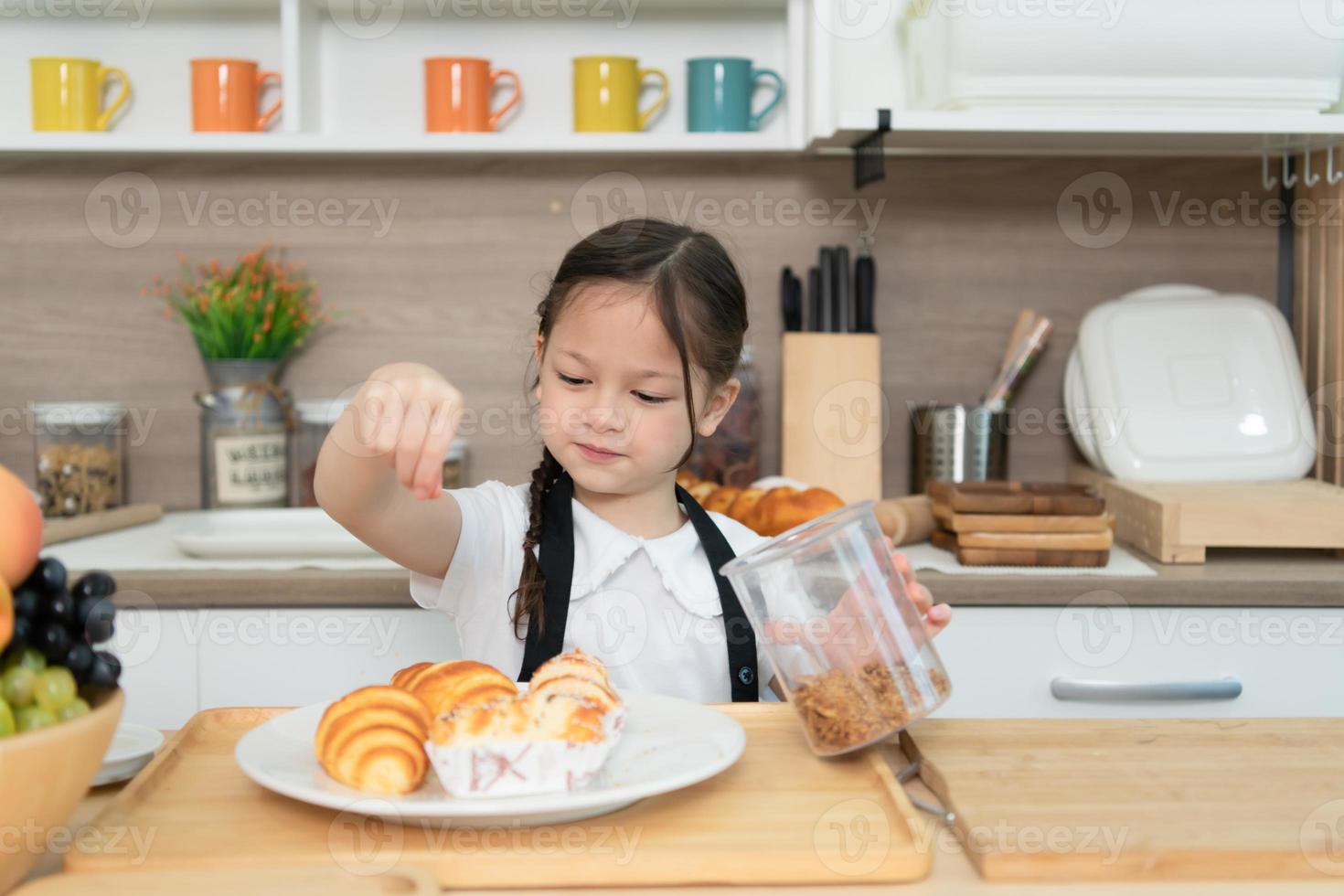 Portrait of a little girl in the kitchen of a house having fun playing baking bread photo