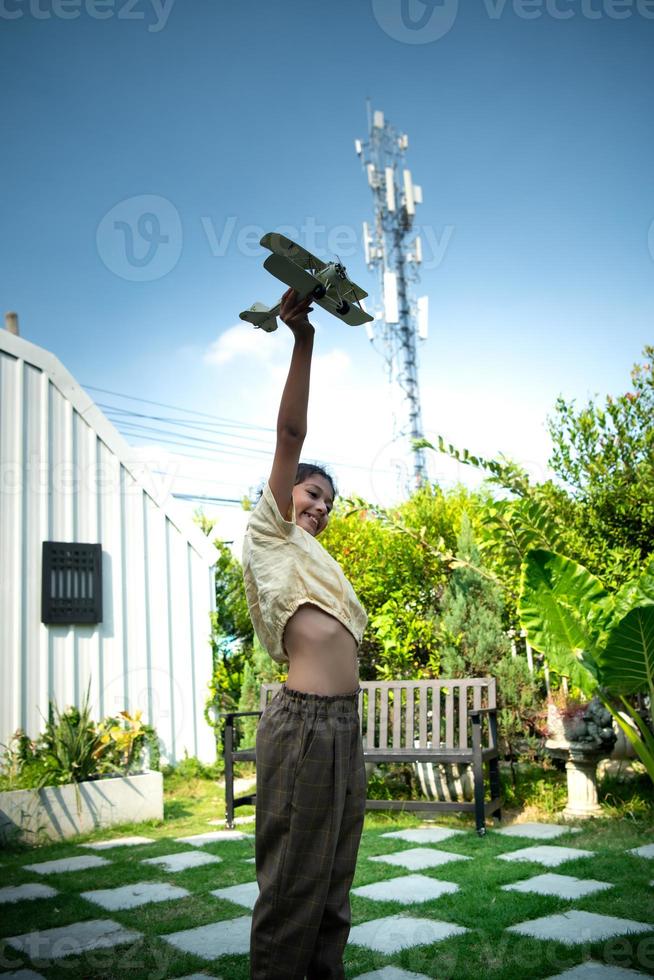 retrato de un pequeño niña en el frente patio trasero. con modelo aeronave cuales es el sueño de un niño quien quiere a ser un piloto. foto