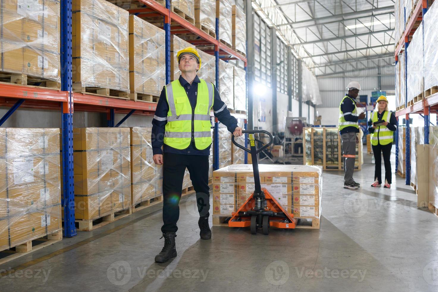 trabajador en auto partes almacén utilizar un carretón a trabajo a traer el caja de auto partes dentro el almacenamiento estante de el almacén esperando para entrega a el coche montaje línea foto