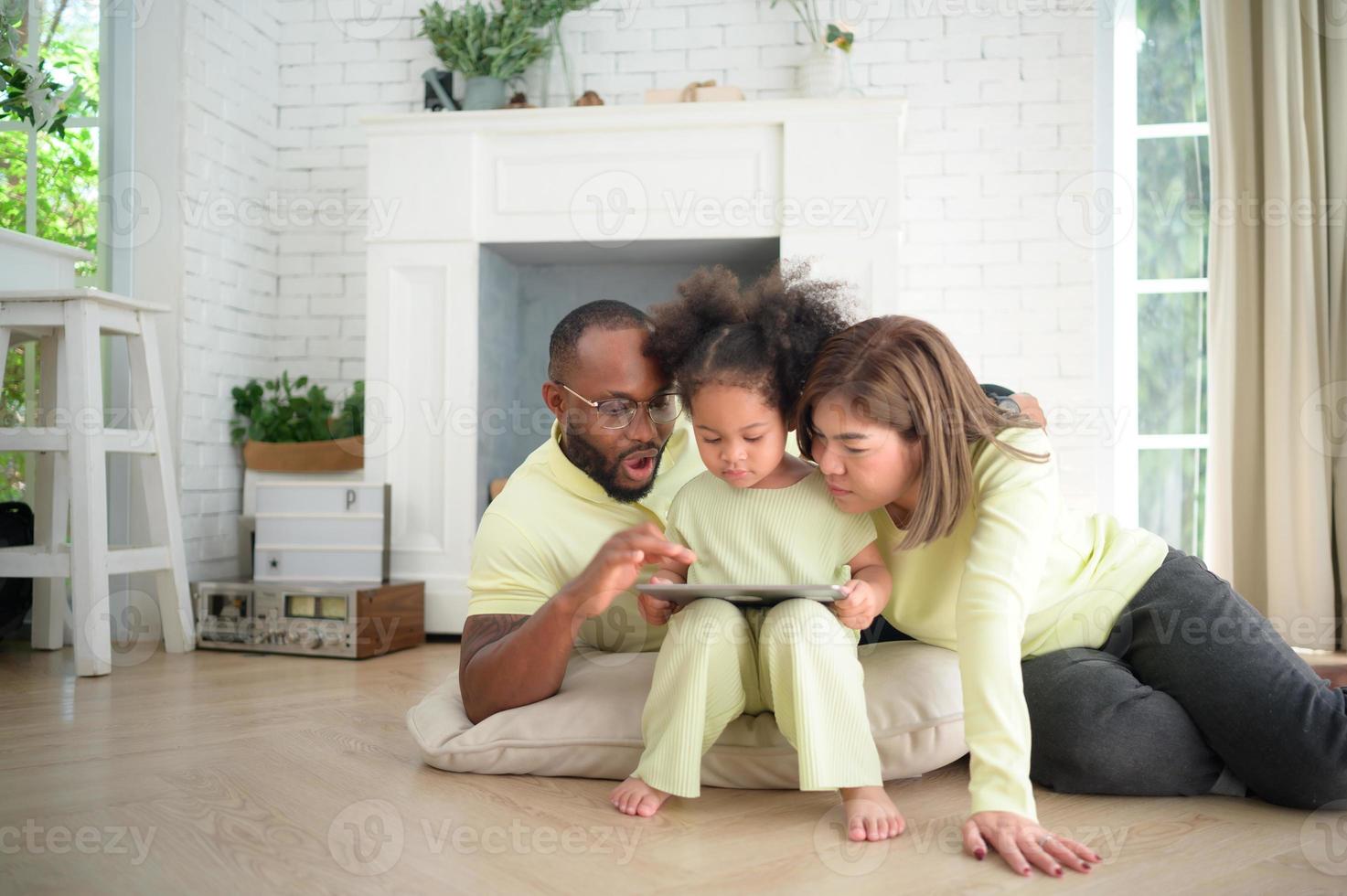 Little children play and learn things in the wide world on tablet. with parents to supervise and help in the living room of the house on vacation photo