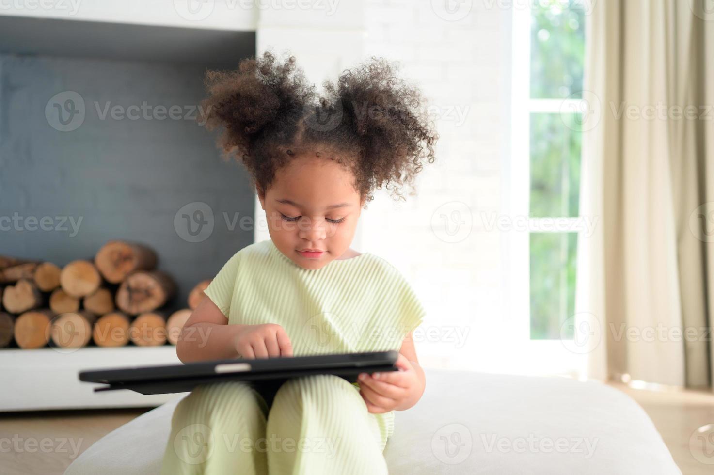 A young bright cute little girl with her trusty tablet that makes her happy and joyful. photo