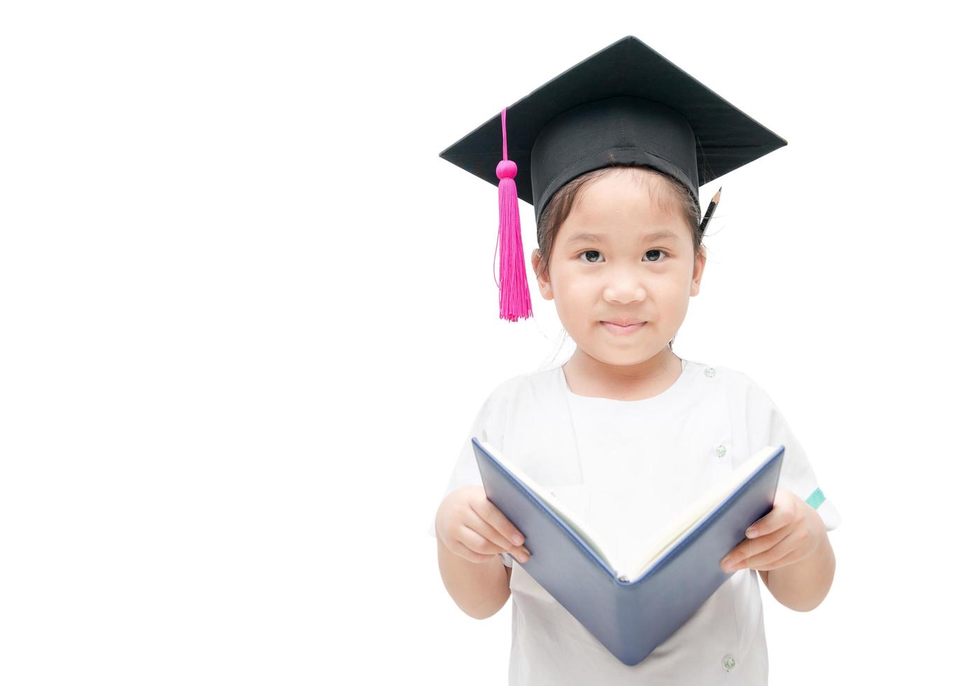 contento asiático colegio niño graduado leyendo libro con graduación gorra foto
