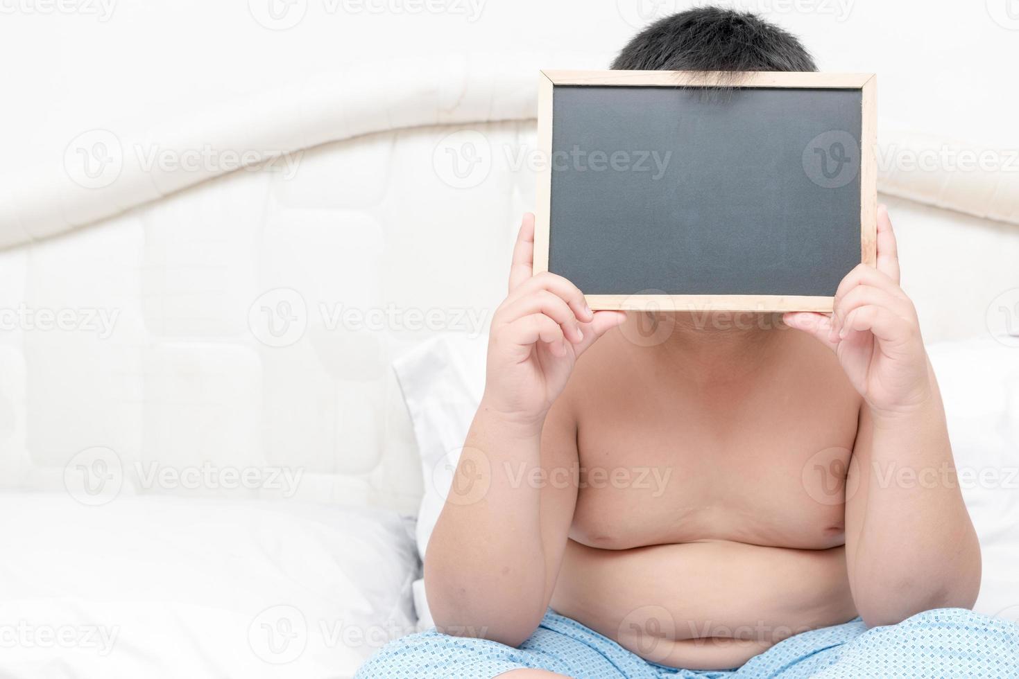 obese fat boy showing blank blackboard photo