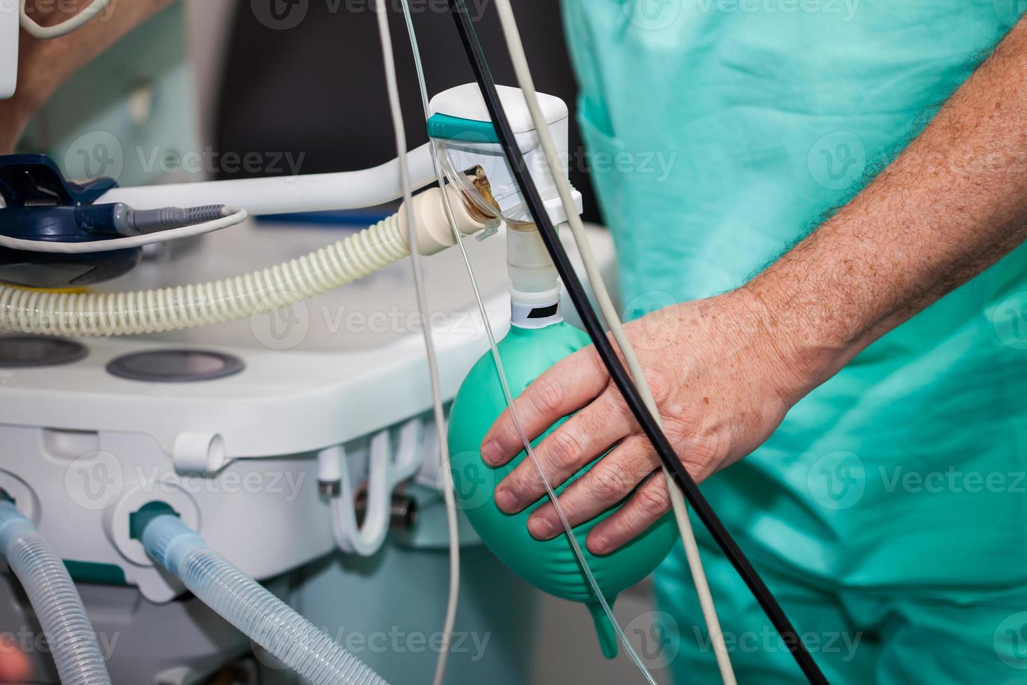 Close up of a doctor hand pressing the anesthesia rebreathing bag while surgical team prepares their patient for surgery photo