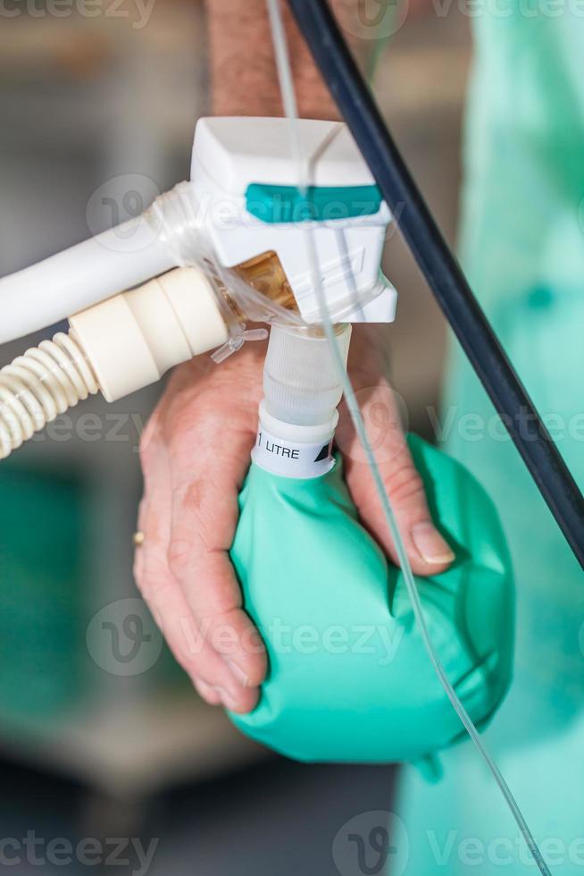 Close up of a doctor hand pressing the anesthesia rebreathing bag while surgical team prepares their patient for surgery photo
