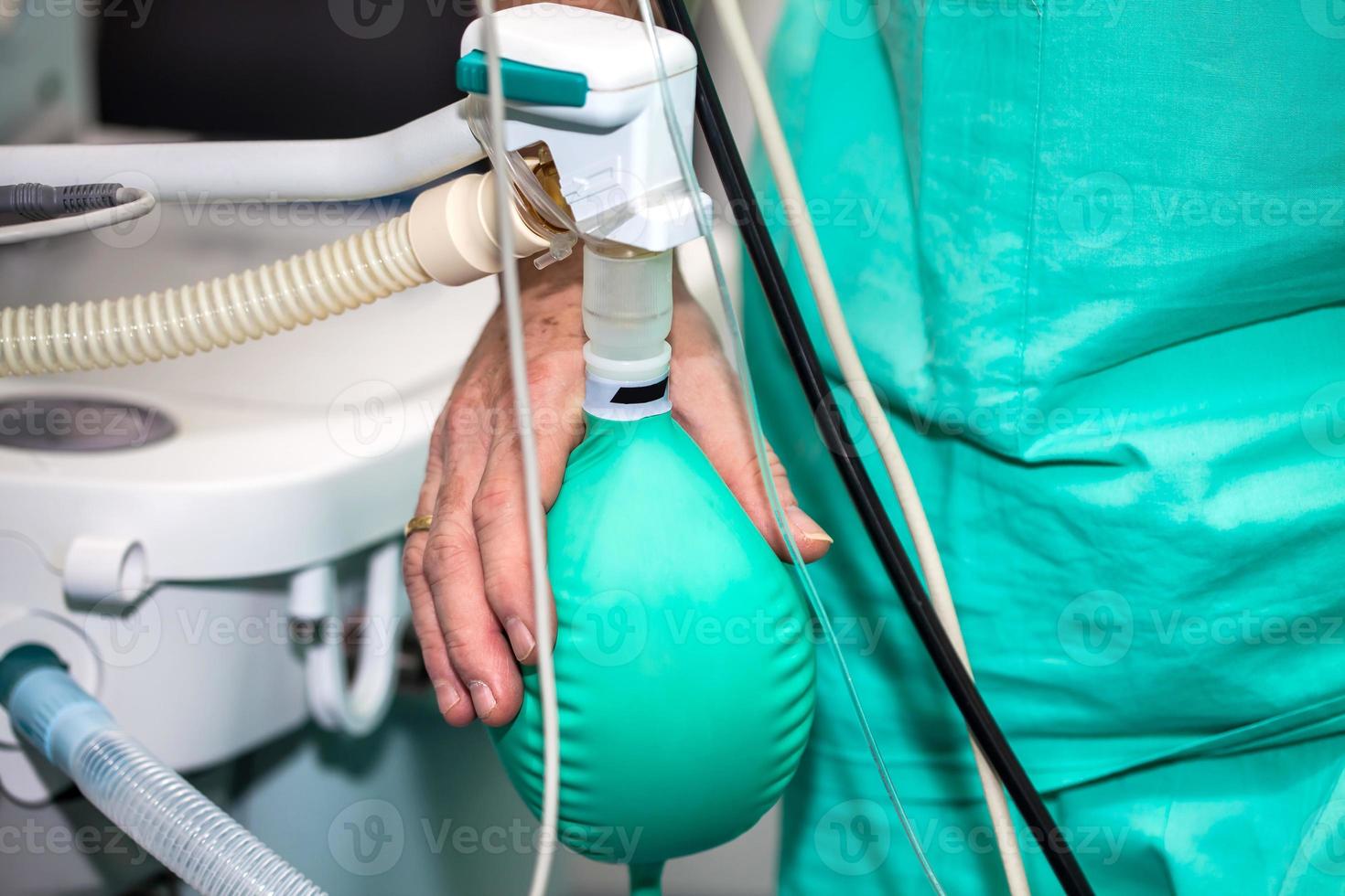 Close up of a doctor hand pressing the anesthesia rebreathing bag while surgical team prepares their patient for surgery photo