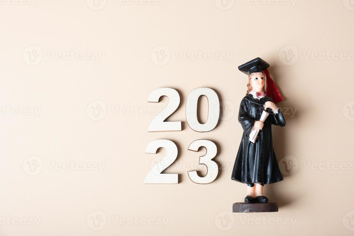 Class of 2023 concept. Wooden number 2023 with graduate statuette on color background photo