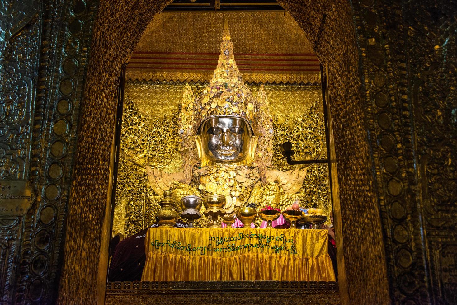 MANDALAY, MYANMAR - JUL 17, 2018-Senior monk wash the face of Mahamuni Buddha image at Mahamuni temple. the most highly revered Buddha image in the country. photo