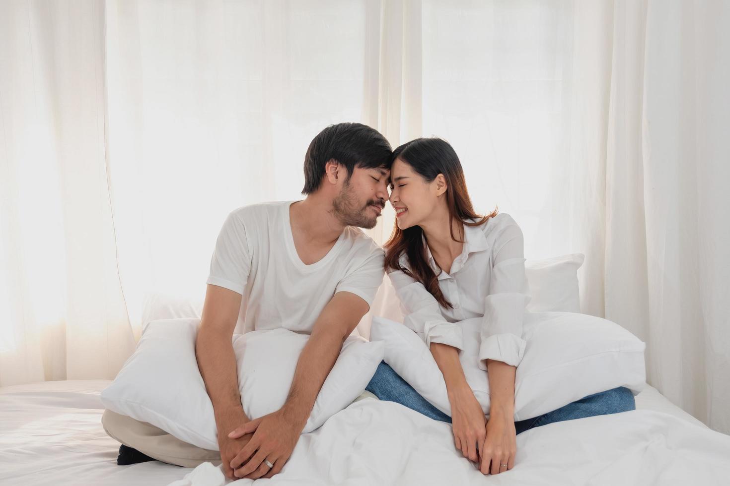 contento joven asiático Pareja abrazando, broma, jugando alegremente en cama a hogar, romántico hora a mejorar familia vinculación familia concepto. foto