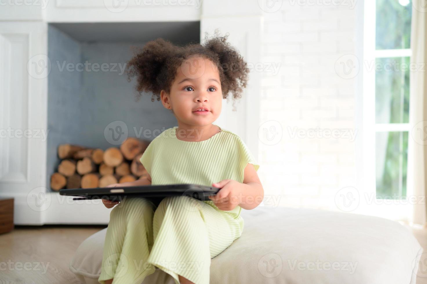 A young bright cute little girl with her trusty tablet that makes her happy and joyful. photo