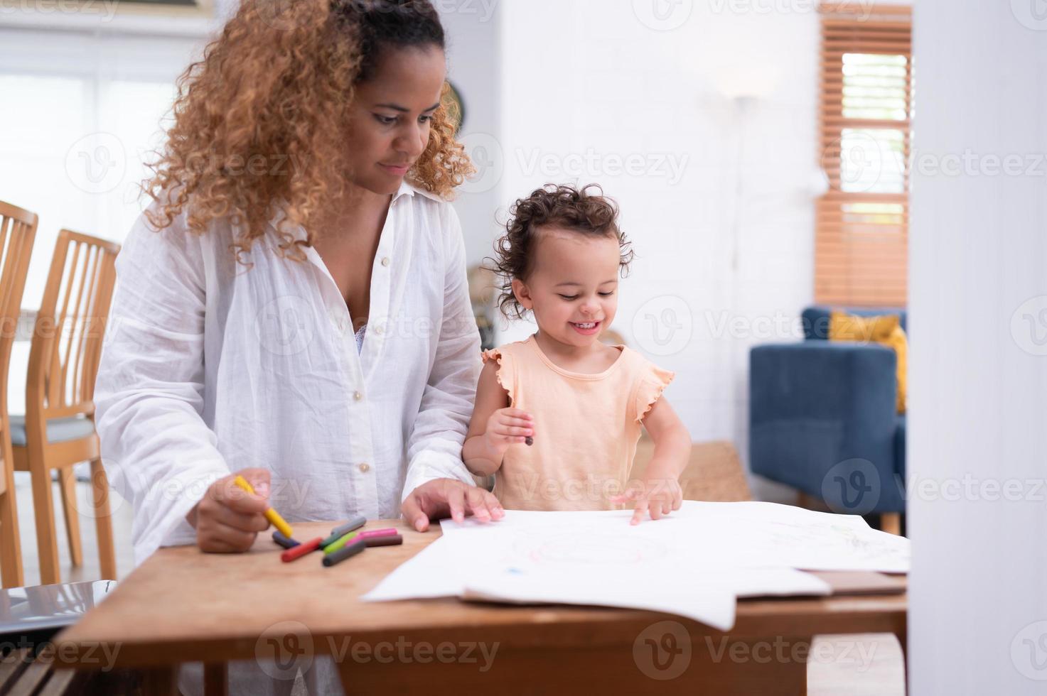 un pequeño niño imaginación es representado mediante de colores lápiz dibujos, con el madre atentamente supervisando en el vivo habitación de el casa. foto