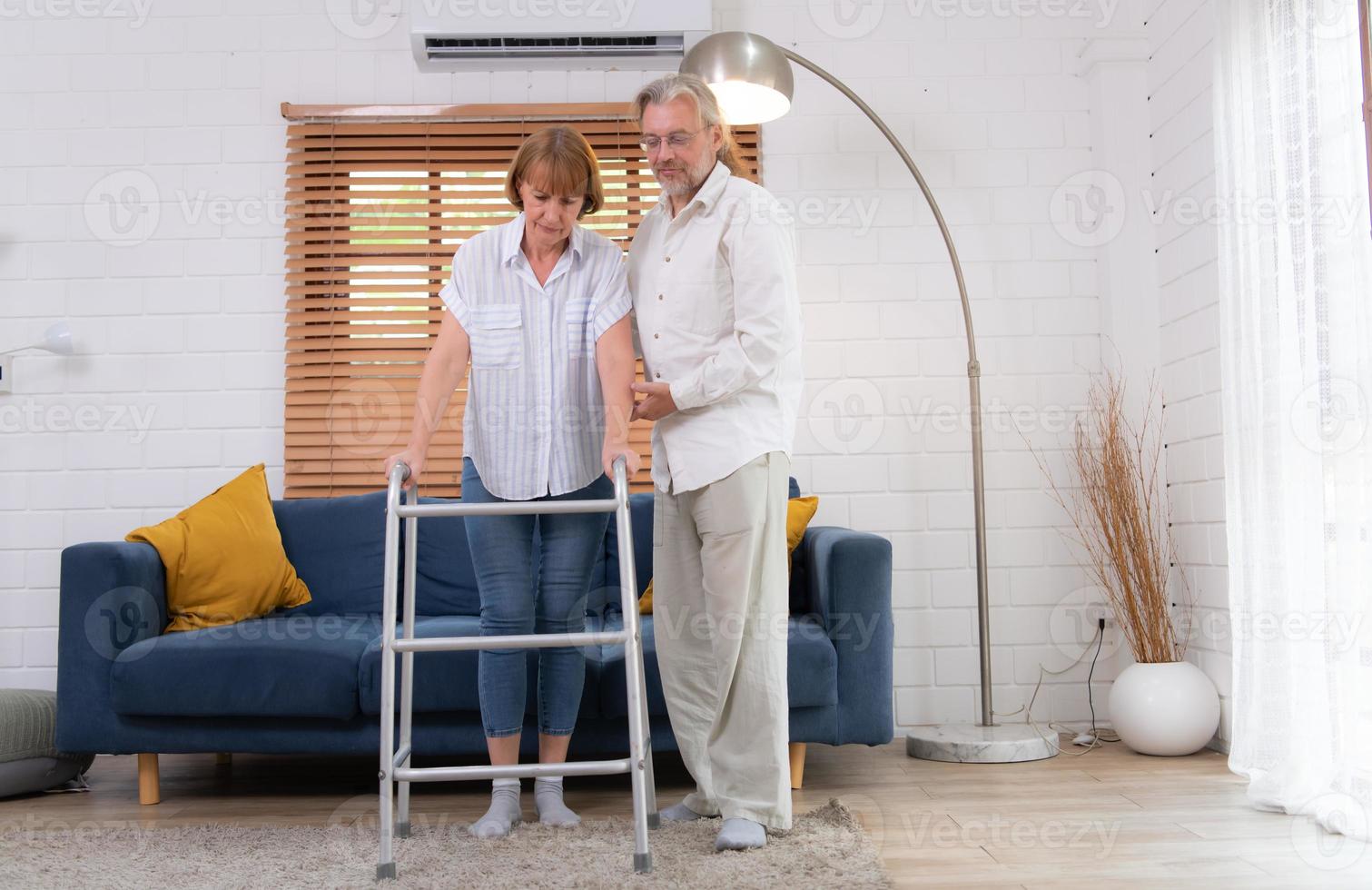 Old couple with his wife, who had to learn to walk after being treated for an osteoarthritis. Must help and take care of each other without children to take care of. photo