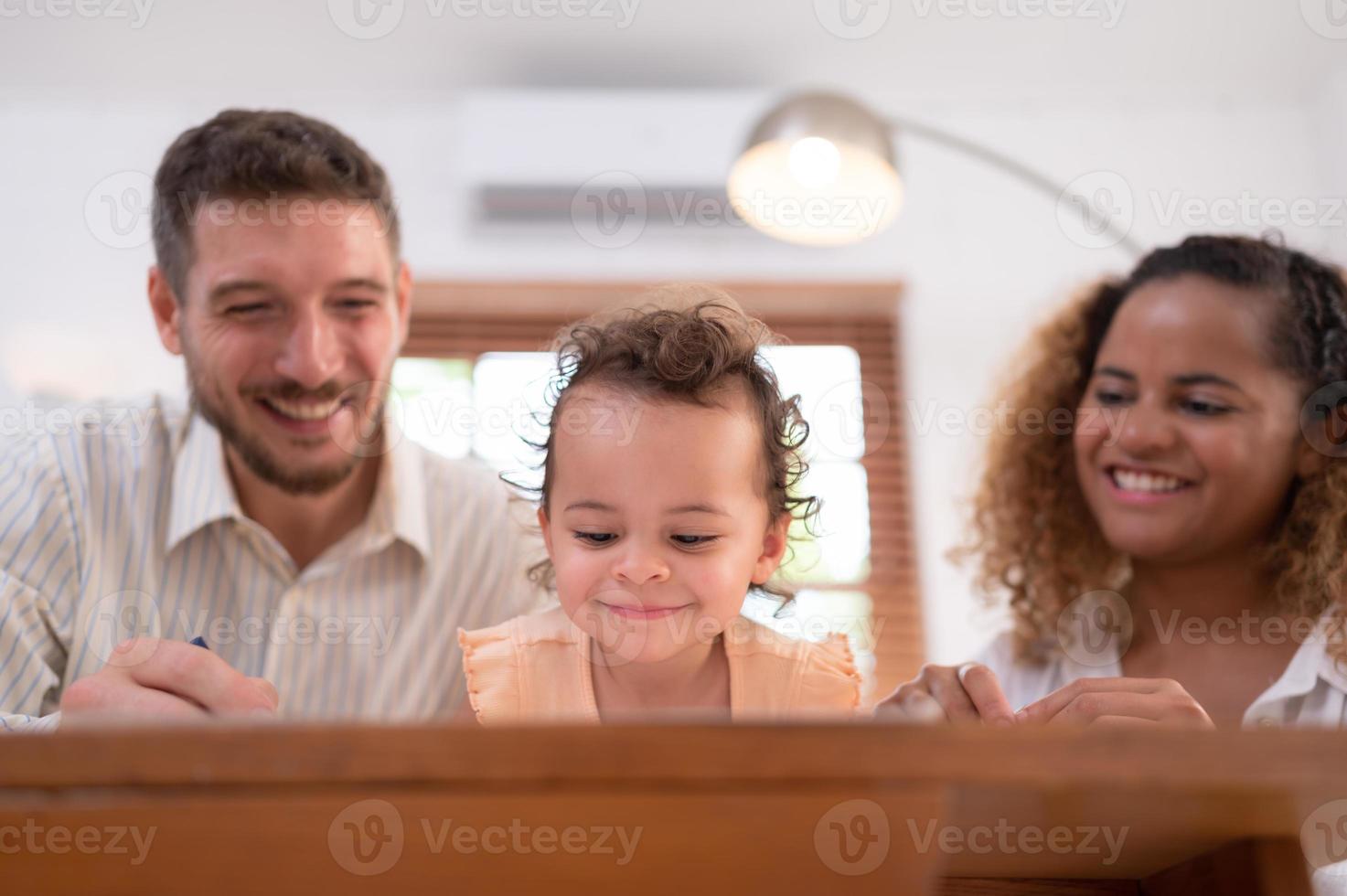 A little child's imagination is represented through colored pencil drawings, with the parents attentively supervising in the living room of the house. photo