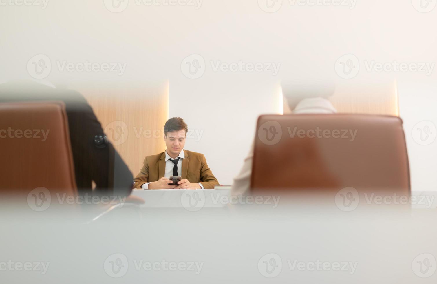 At the meeting room, a young businessman sitting in a secret meeting with many other businessmen the atmosphere is good. have a happy smile photo