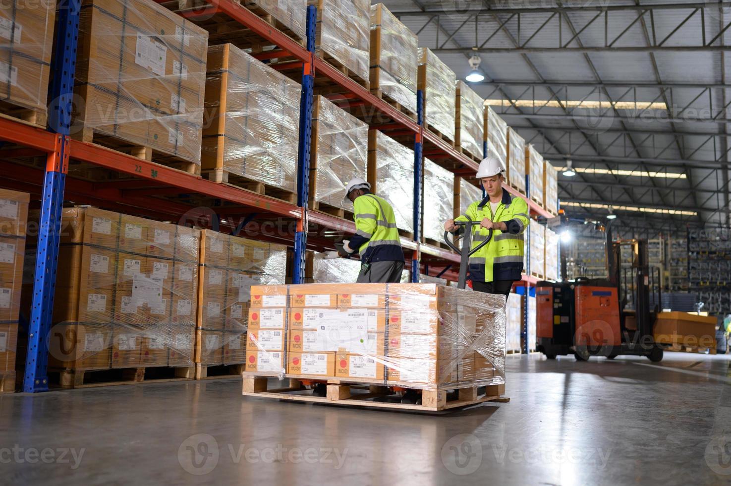 Worker in auto parts warehouse use a handcart to work to bring the box of auto parts into the storage shelf of the warehouse waiting for delivery to the car assembly line photo