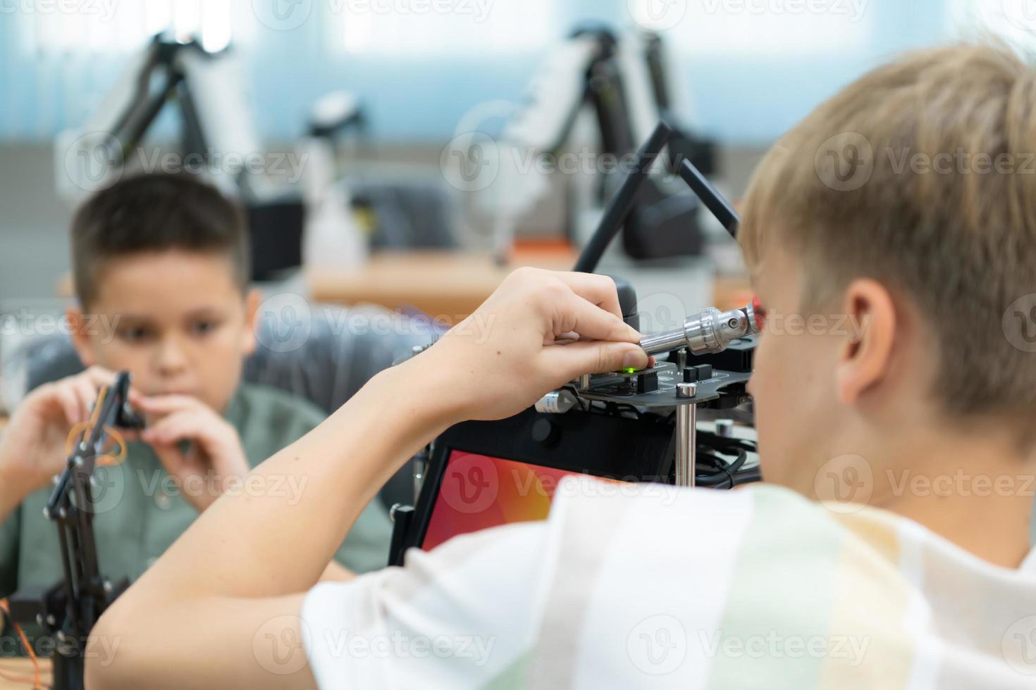 niños utilizando el mano robot tecnología, estudiantes son estudiando tecnología, cuales es uno de el vástago cursos foto