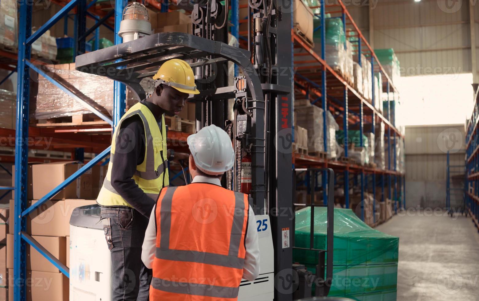 Manager with foreman discuss about the equipment used to move goods in the warehouse. photo