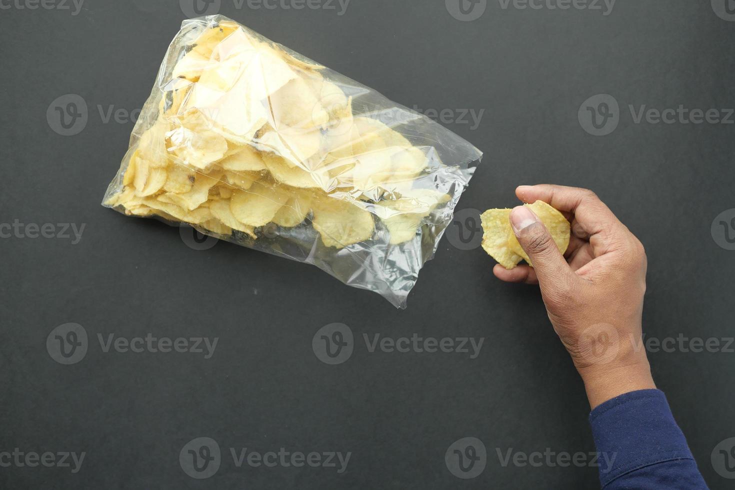 men pick potato chips from a plastic packet photo