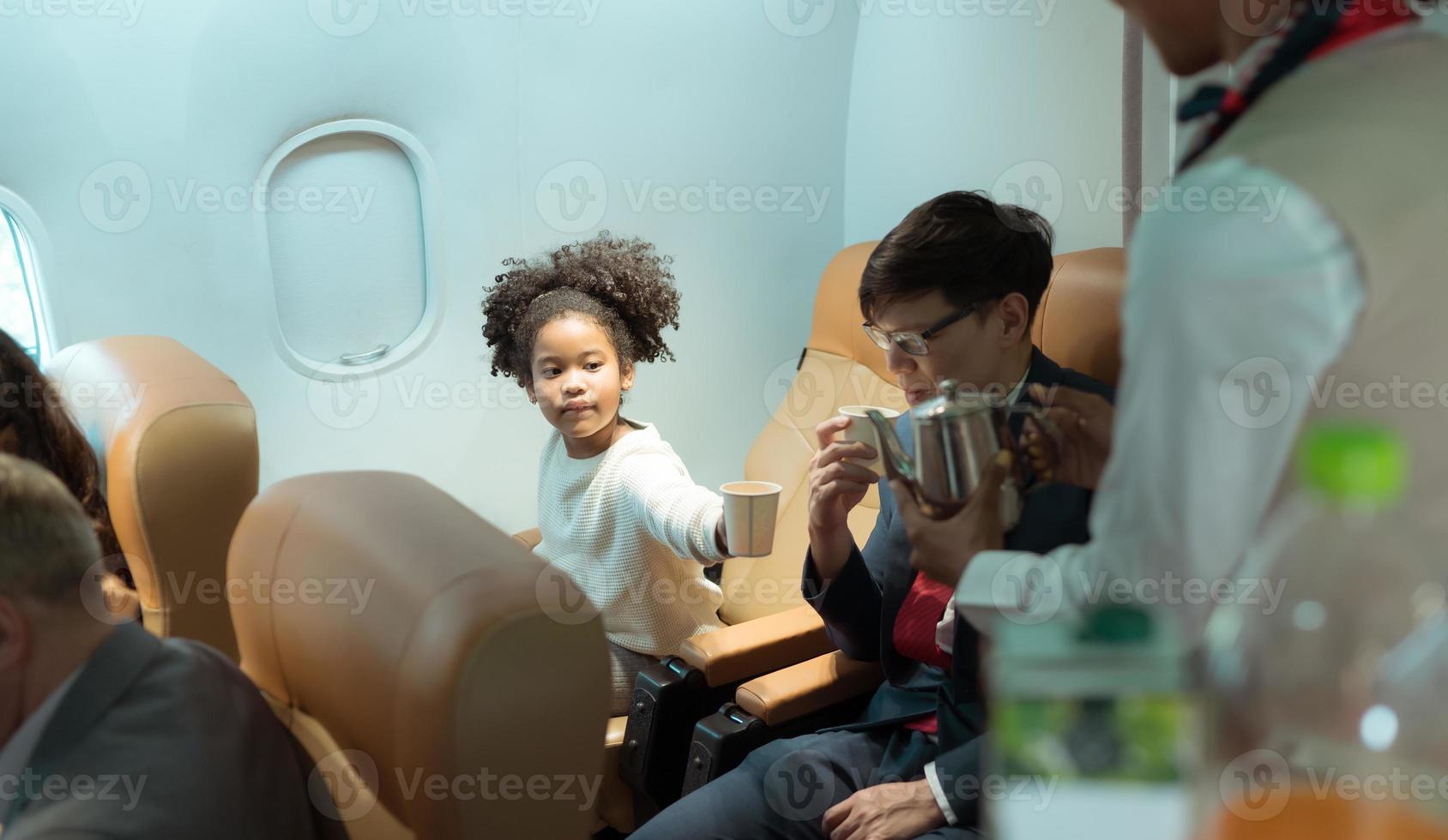 Flight attendant serving beverages to business class passengers photo