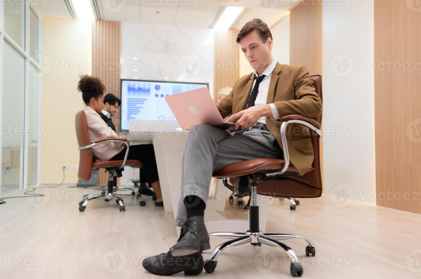 At the meeting room, a young businessman sitting in a secret meeting with many other businessmen the atmosphere is serious photo