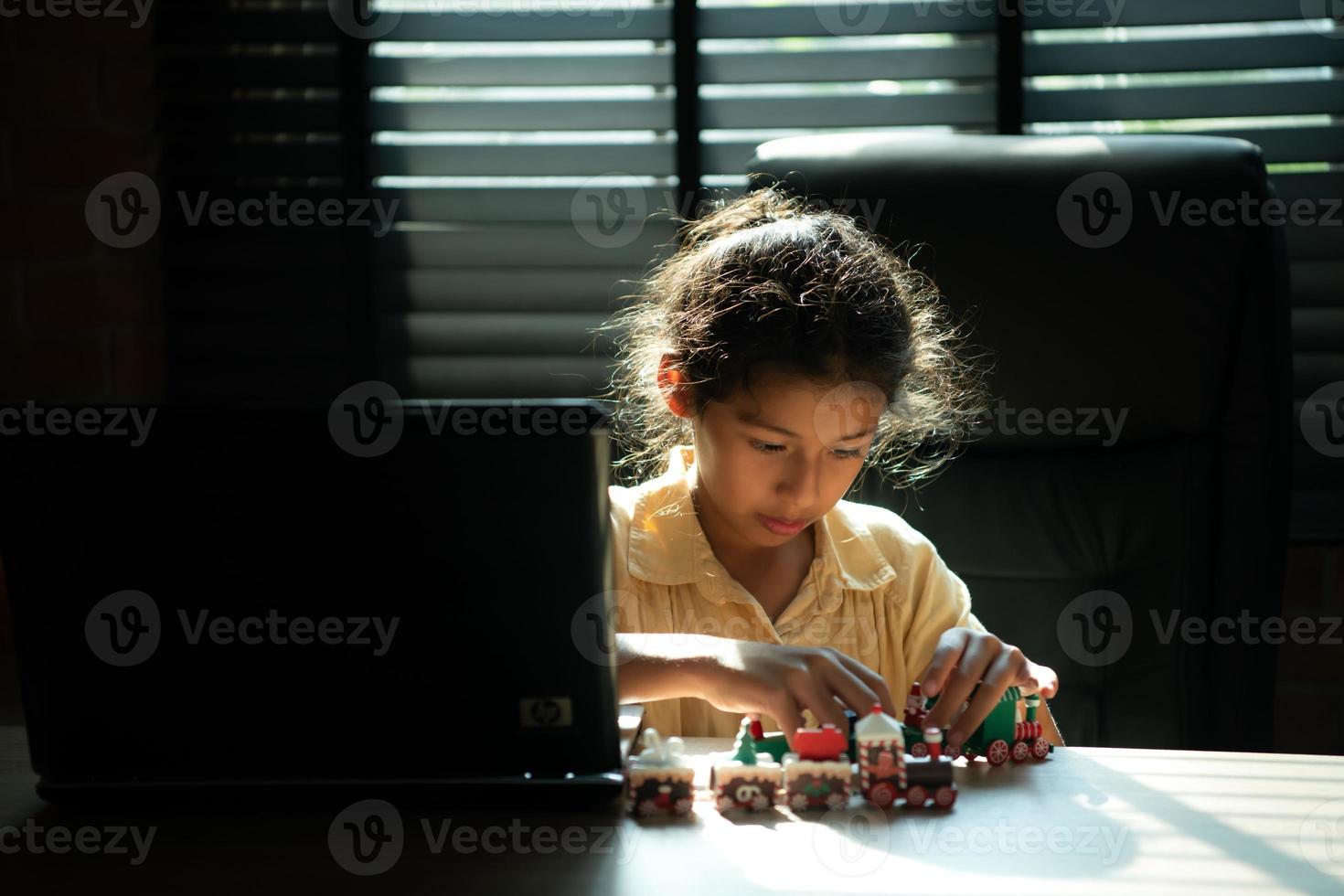 Portrait of little girl in the office room of house, They are having fun playing with toy trains photo