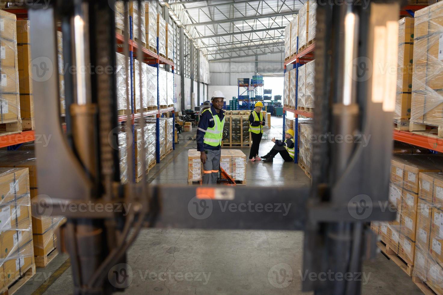 trabajador en auto partes almacén utilizar un carretón a trabajo a traer el caja de auto partes dentro el almacenamiento estante de el almacén esperando para entrega a el coche montaje línea foto