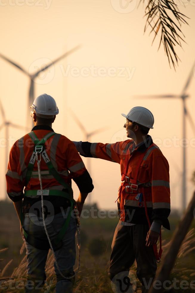 Engineers working on wind farms for renewable energy are responsible for maintaining large wind turbines. Returning from work during while the evening sun shines a beautiful golden light upon both of photo