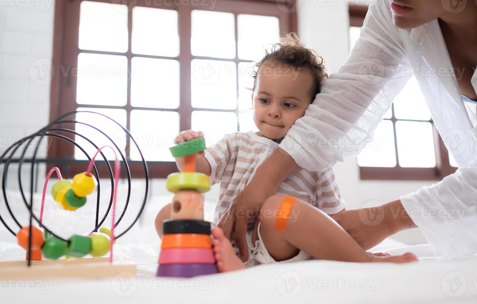 madre con pequeño niña tener divertido jugando con tu nuevo juguetes en el dormitorio juntos. juguetes ese mejorar para niños pensando habilidades. foto