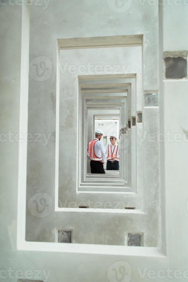 Both of construction engineers verify the constructed precast concrete wall slabs' quality. also to oversee significant construction projects in the construction zone photo