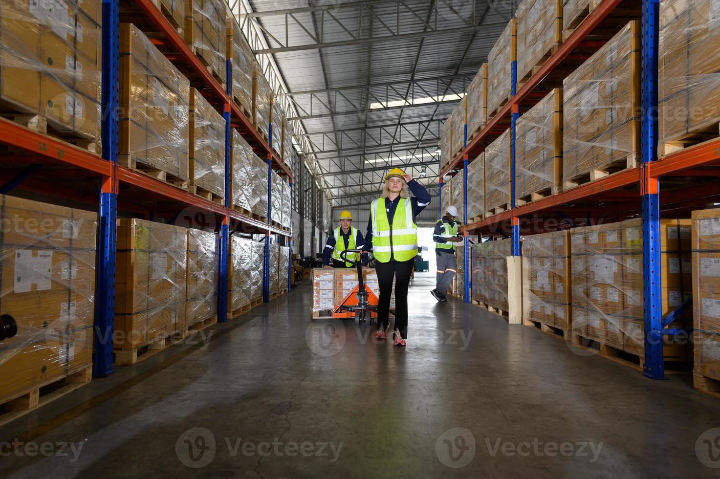 Worker in auto parts warehouse use a handcart to work to bring the box of auto parts into the storage shelf of the warehouse waiting for delivery to the car assembly line photo