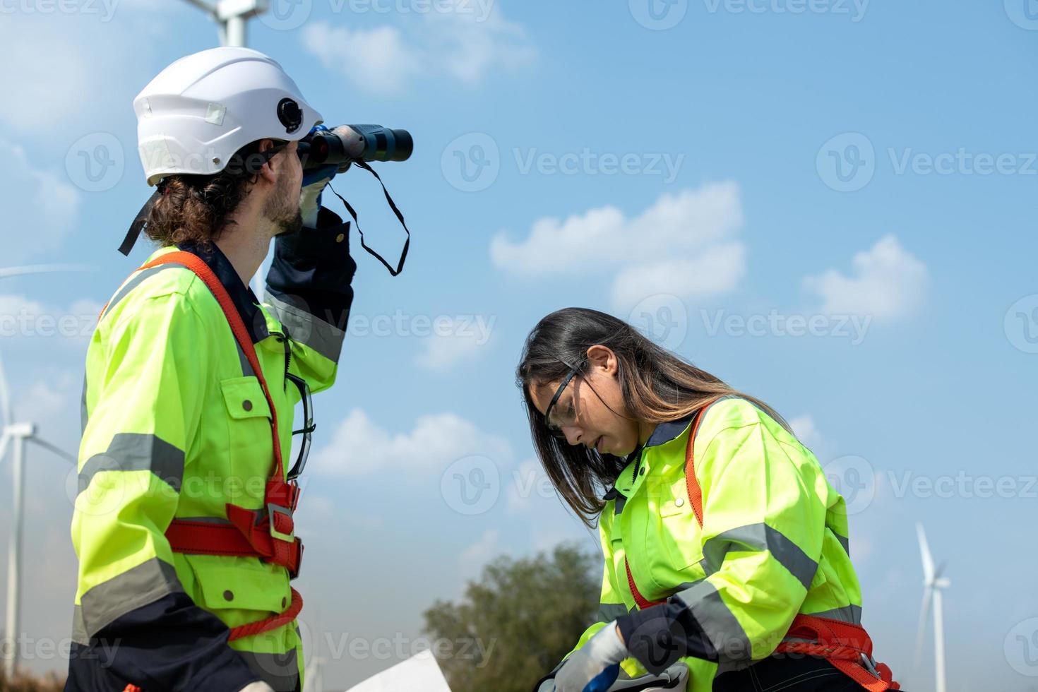 Man and female engineer stationed at the Natural Energy Wind Turbine site. with daily audit tasks of major wind turbine operations that transform wind energy into electrical electricity photo