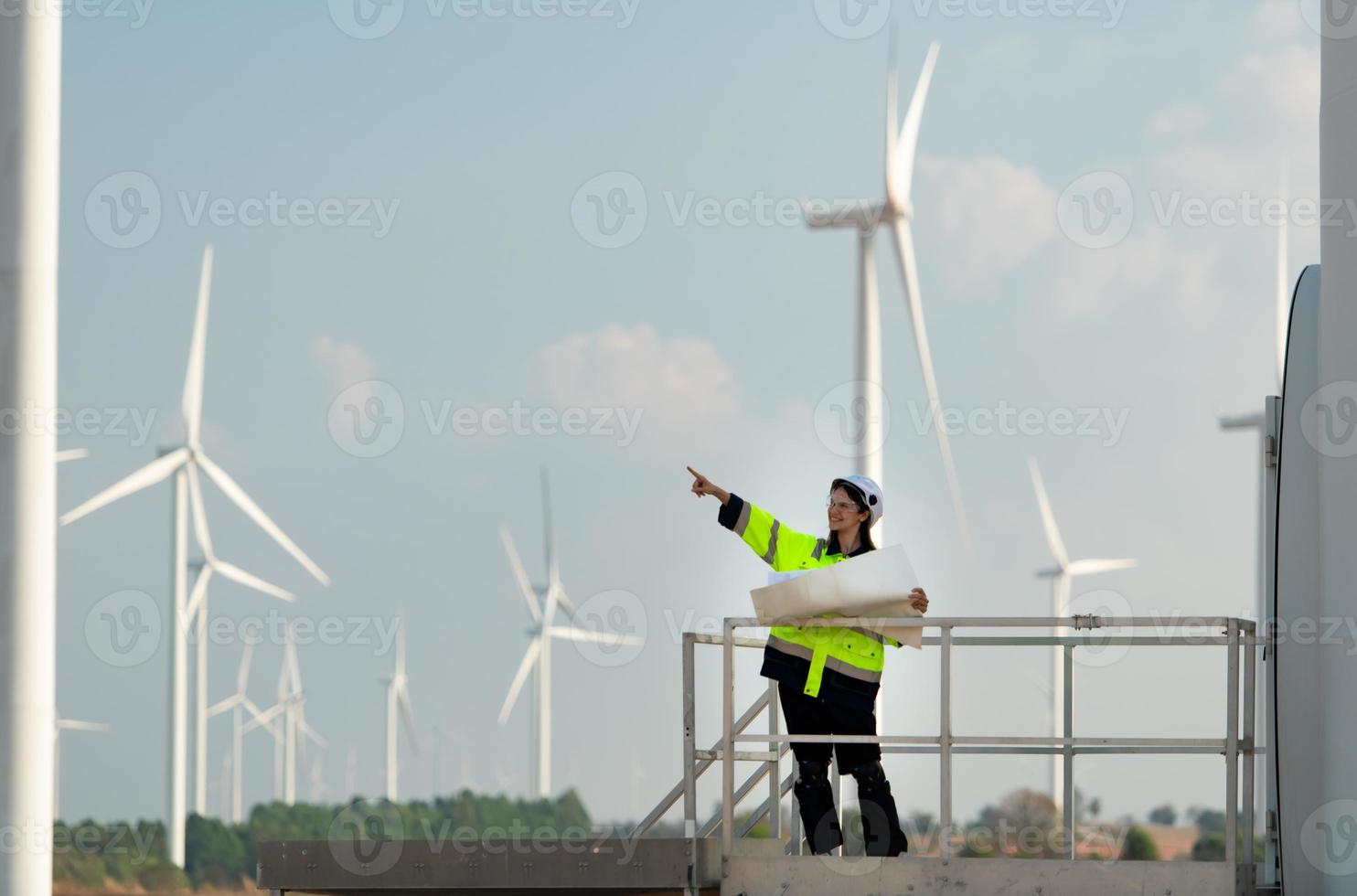retrato de hembra ingeniero a natural energía viento turbina sitio con el misión de siendo responsable para tomando cuidado de grande viento turbinas foto