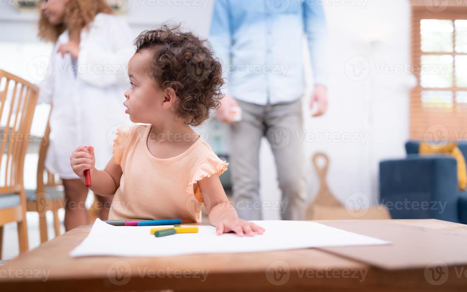 A little child's imagination is represented through colored pencil drawings, with the mother attentively supervising in the living room of the house. photo