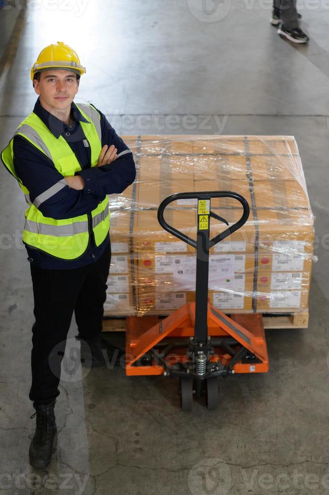 Worker in auto parts warehouse use a handcart to work to bring the box of auto parts into the storage shelf of the warehouse waiting for delivery to the car assembly line photo