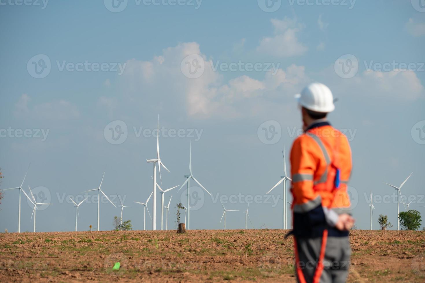 ingeniero a natural energía viento turbina sitio con un misión a tomar cuidado de grande viento turbinas utilizar un walkie película sonora a comunicar con un colega trabajando en parte superior de el viento turbina. foto