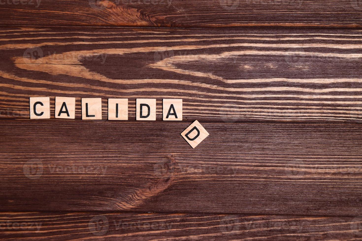 Calidad, quality spanish word, lettering on wooden background photo